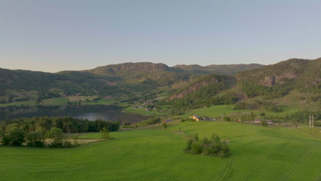 Lush,-beautiful-farm-house-overlooking-mountain-lake.-Aerial