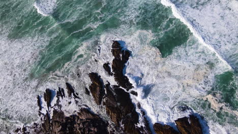 Top-view-of-waves-crashing-into-rocks-on-coastline,-Kwaaiwater,-Hermanus