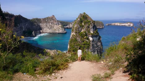 Woman-traveler-walking-on-Nusa-Penida-island-viewpoint-overlooking-the-coastal-cliffs