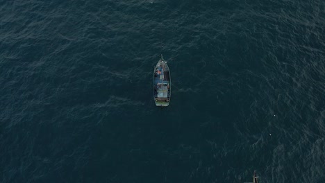 Filmische-Luftdrohnenaufnahme-Eines-Kleinen-Fischerbootes,-Das-Im-Tiefblauen-Meer-Fischt