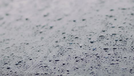 Close-up-footage-of-raindrops-slowly-rolling-down-a-dark-car-window-during-a-downpour