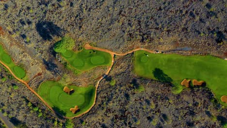 Aerial-top-down-view-of-well-kept-Manele-Golf-Course-standing-out-against-rugged-landscape---Lanai,-Hawaii