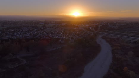 Glowing-golden-sunrise-over-King-City,-California---ascending-aerial-view