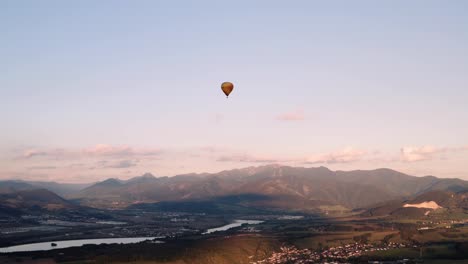 Panoramic-aerial-view-of-hot-air-balloon-floating-in-golden-hour-sky