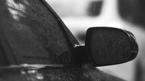 Close-up-footage-of-raindrops-slowly-rolling-down-from-a-car's-side-window-and-mirror-during-a-rainstorm