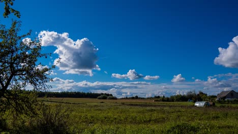 Blue-sky-autumn-timelapse-in-4K-with-spectacular-clouds,-with-forest,-apple-tree-and-a-homestead-in-the-background