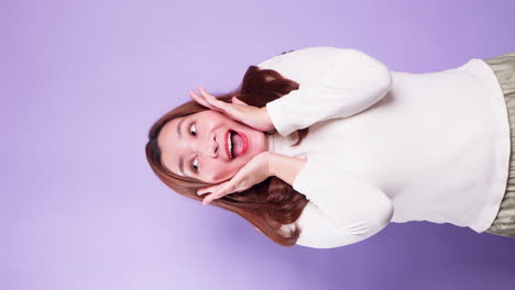 Vertical-of-Portrait-of-young-Asian-lady-with-a-positive-expression,-joyful-surprise-funky-and-looking-at-camera-over-violet-background