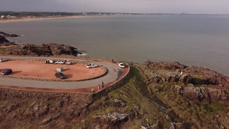 Aerial-orbit-of-tourist-and-parking-cars-at-lookout-viewpoint-in-punta-ballena,-uruguay