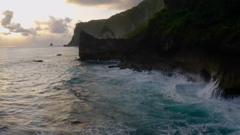 Luftaufnahme-Von-Großen-Wellen,-Die-Bei-Sonnenuntergang-In-Die-Felsigen-Klippen-Der-Insel-Nusa-Penida-Einbrechen