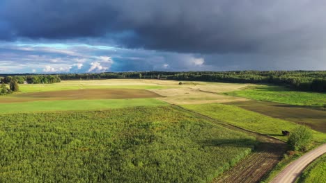 Agricultural-fields-with-stormy-weather-threatening-rain,-aerial-landing-down