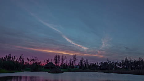 Rural-cabin-in-a-winter-landscape-at-sunset-with-the-lake-water-freezing-on-the-ice---colorful,-wide-angle-time-lapse