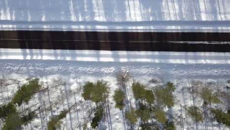 Straight-down-camera-moving-left-to-right-above-the-black-road-middle-of-white-snow