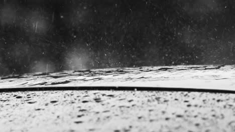 Thick-raindrops-shatter-on-the-roof-of-a-car-during-a-heavy-rainstorm---close-up-shot