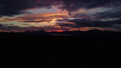 Drone-shot-of-late-sunset-over-fields-and-mountains-with-dramatic-sky
