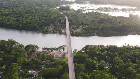 Aerial-high-view-Bridge-Connecting-Forested-Riverbanks,-wetlands-in-Background