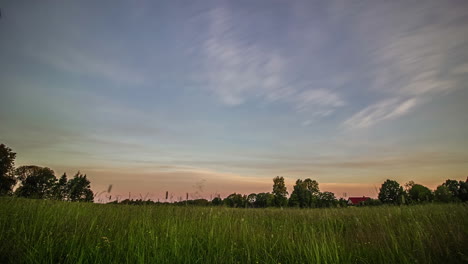 Timelapse-shot-of-white-cloud-movement-along-blue-sky-over-green-grasslands-during-evening-time