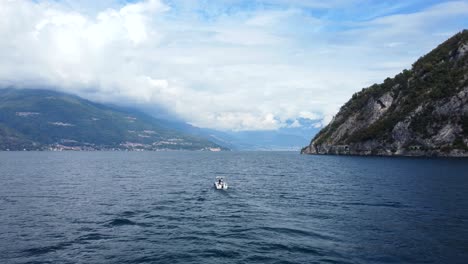 Drohnenschussboot,-Das-In-Wunderschönem-Blauem-Wasser-Segelt,-Umgeben-Von-Bergen