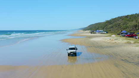 4WD-Driving-On-Camping-Beach-Beside-Blue-Ocean-Waves-In-Australia,-4K-Aerial-Drone