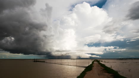 Tief-Liegende-Stürmische-Wetterfrontwolken-Rollen-Horizontal-über-Den-Tonle-Sap-See-Mit-Fischnetzen-Im-Vordergrund-Und-Bewegtem-Regen,-Während-Die-Monsunzeit-In-Südostasien-Einsetzt