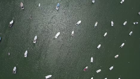 Aerial-view-overlooking-moored-boats-on-the-coast-of-Plymouth,-USA---rotating,-tilt,-drone-shot