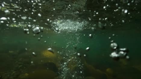 Slow-motion-underwater-shot-of-a-stone-falling-into-a-river