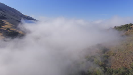 Fast-drone-flight-over-a-valley-and-then-through-low-valley-mist-and-fog