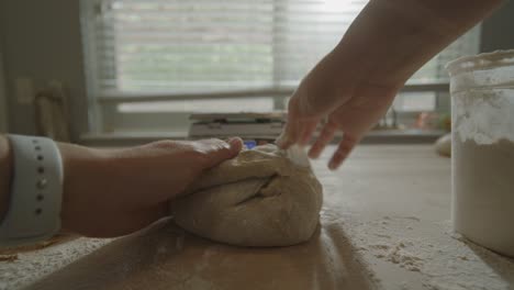 POV-of-hands-shaping-sourdough-bread-on-kitchen-counter