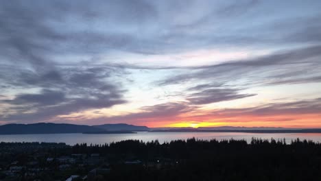 Aufsteigende-Luftaufnahme-Eines-Hübschen-Sonnenuntergangs-über-Den-Inseln-Von-San-Juan-Mit-Den-Wäldern-Von-Bellingham-Im-Vordergrund