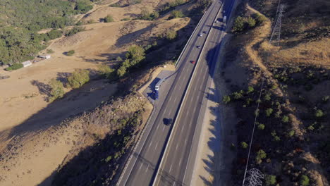 Broken-down-truck-with-roadside-assistance-by-a-busy-highway,-aerial-view