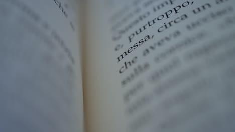 Camera-scrolls-across-a-page-of-an-italian-book-slow-motion-macro-shot-shallow-focus