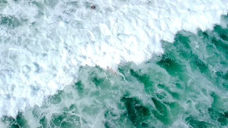 Surfer-paddles-through-white-wash-at-oceanside-pier