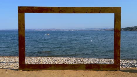 Wooden-frame-on-beach-sea-shore-for-location-decoration-of-celebratory-seaside-events-and-boat-in-background