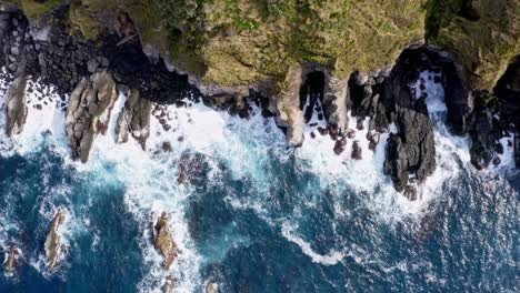 Foamy-waves-washing-rugged-rocky-coastal-cliffs-of-Azores,-overhead