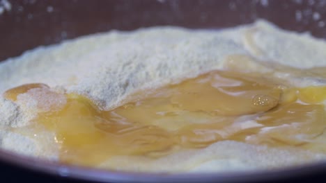 Raw-egg-puddles-on-a-plate-of-flour-before-a-second-egg-splashes-onto-the-flour