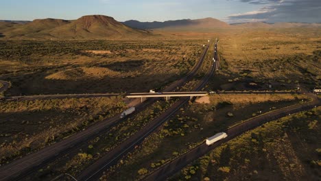 Aerial-view-of-Light-Traffic-on-Interstate-40-and-Highway-93-Overpass-near-Kingman-Arizona-at-Sunset,-Mountains-in-the-Background,-Golden-hour