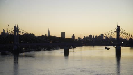 London-dawn-skyline-reflected-in-Thames-seen-through-Albert-Bridge-from-Battersea-Bridge-looking-towards-Vauxhall-and-the-city-4K