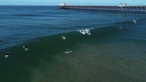 Male-surfer-drops-in-on-wave-at-oceanside-pier