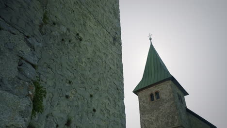 Toma-Recursiva-Inferior-De-La-Antigua-Torre-Y-La-Iglesia-En-La-Cima-De-La-Colina-Con-Un-Hermoso-Cielo-Azul-Y-Sol-Detrás-De-La-Iglesia-En-Verano,-Kum-Eslovenia