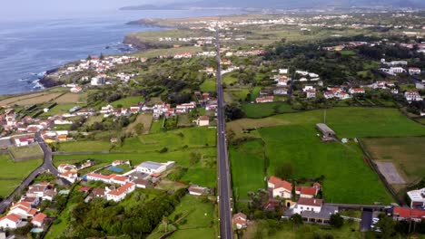 Long-straight-highway-between-towns-on-coastline-of-Azores,-aerial
