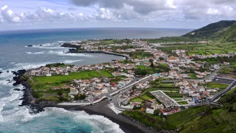 Town-on-rocky-atlantic-coastline-washed-by-large-waves,-Azores,-aerial