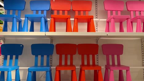 For-toddlers,-several-little-chairs-in-the-colors-red,-blue,-and-pink-are-grouped-together-in-the-shelves-for-sale-display