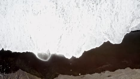 Foaming-ocean-waves-washing-black-sand-beach-of-Azores,-overhead-view