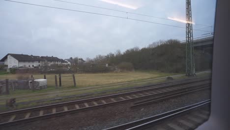 View-from-train-window-with-underpass-railroad-tracks-power-lines-and-houses