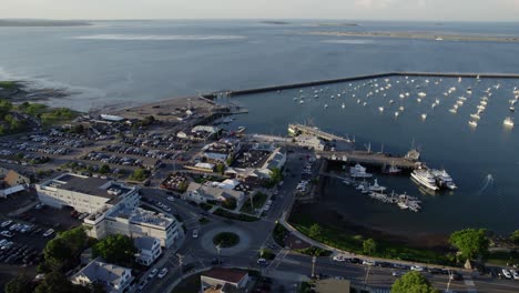 Aerial-view-overlooking-the-harbor-of-Plymouth,-golden-hour-in-Massachusetts,-USA---rising,-tilt,-drone-shot