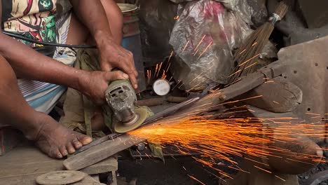 Closeup-of-worker-using-grinder-with-no-safety-equipment-barefoot,-Bangladesh