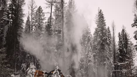 Industrial-timber-manipulator-saw-machine-takes-snow-covered-trees-down-in-snowstorm,-dramatic,-part-of-a-large-series