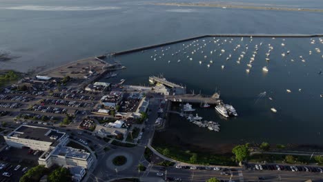 Aerial-view-of-boats-and-the-harbor-of-Plymouth,-sunny,-summer-evening-in-USA---pan,-drone-shot