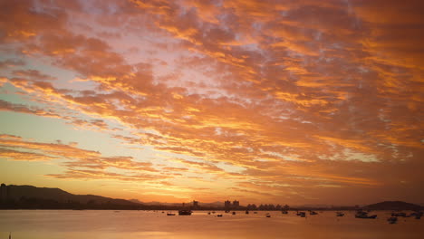Timelapse-of-a-gorgeous-bay-in-Florianopolis,-Brazil,-with-fishing-boats-and-sailboats-anchored-in-the-golden-hour-light-in-the-end-of-a-wonderful-day
