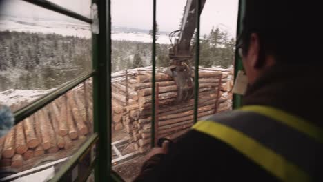 First-person-POV-blue-collar-tradesman-operates-industrial-timber-logging-manipulator-arm-claw-tractor-from-inside-cabin-with-joystick-1