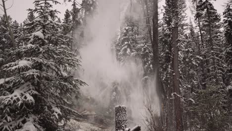 Tight-close-shot-industrial-timber-manipulator-saw-machine-takes-snow-covered-trees-down-in-snowstorm,-dramatic,-part-of-a-large-series